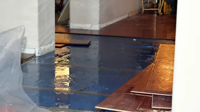 Wet hardwood flooring lifted and covered with plastic sheeting
