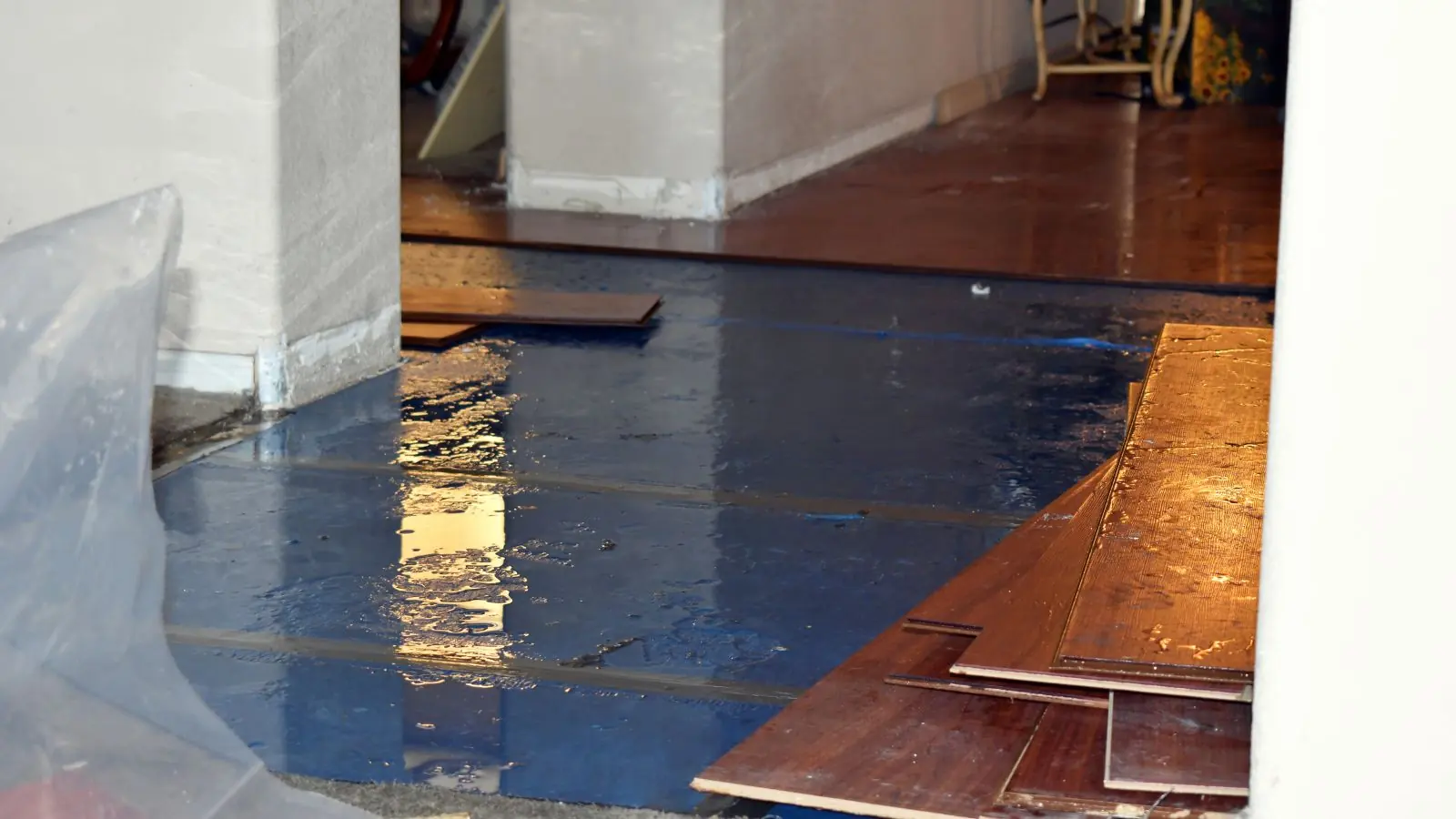 Wet hardwood flooring lifted and covered with plastic sheeting